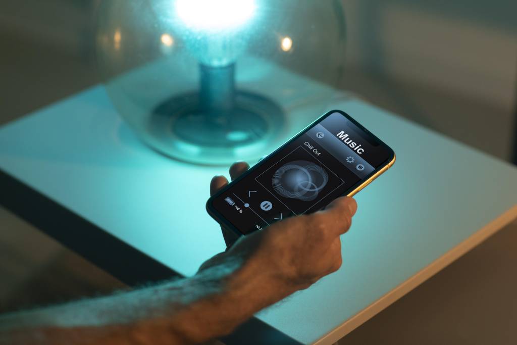 muž ovládajúci osvetlenie v inteligentnej domácnosti cez smartfón